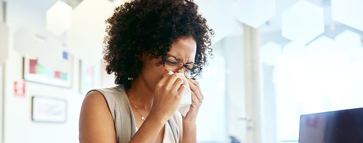 woman sneezing into tissue